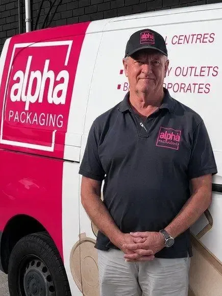 An Alpha Packaging driver beside a branded delivery van